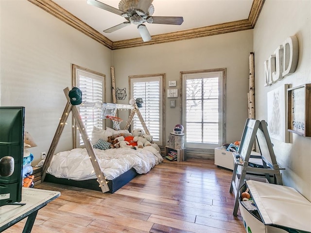 bedroom with a ceiling fan, ornamental molding, and hardwood / wood-style floors