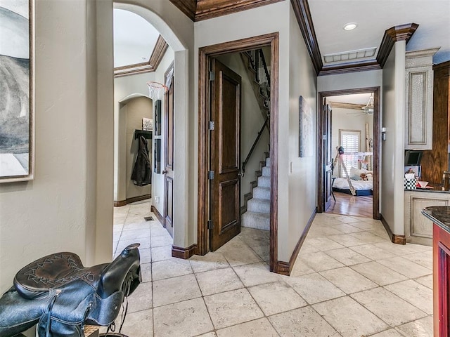 hall featuring light tile patterned floors, baseboards, visible vents, arched walkways, and crown molding