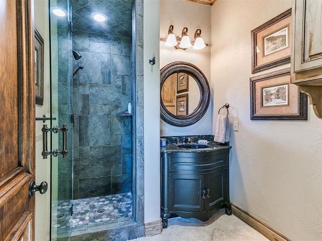 bathroom featuring a stall shower, tile patterned flooring, baseboards, and vanity