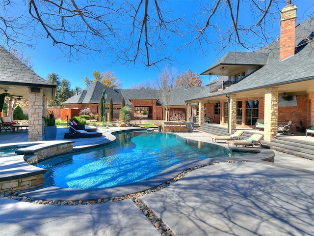 view of pool with a patio area, a pool with connected hot tub, and fence