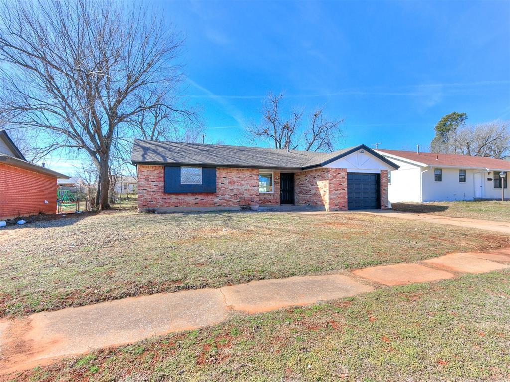 view of front of house featuring an attached garage, brick siding, driveway, and a front yard