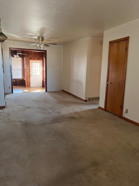 spare room featuring baseboards, a ceiling fan, visible vents, and light colored carpet