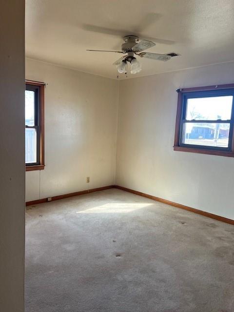 carpeted empty room featuring a ceiling fan and baseboards