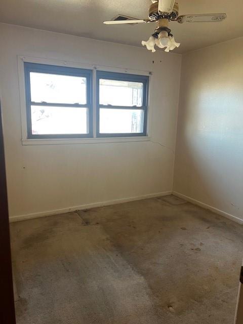 carpeted spare room with baseboards and a ceiling fan