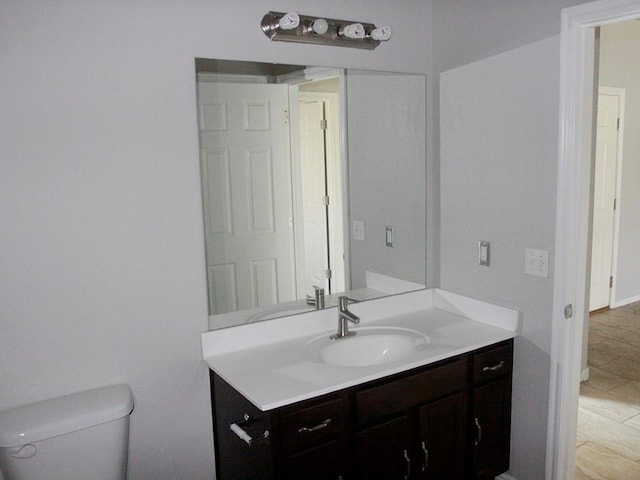 bathroom with toilet, baseboards, and vanity