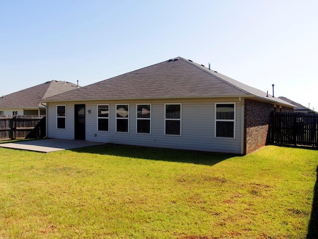 rear view of property featuring a patio, a fenced backyard, brick siding, a shingled roof, and a yard