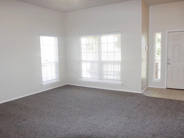 entrance foyer featuring baseboards, light tile patterned flooring, and light colored carpet