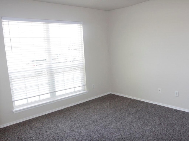 empty room featuring carpet and baseboards