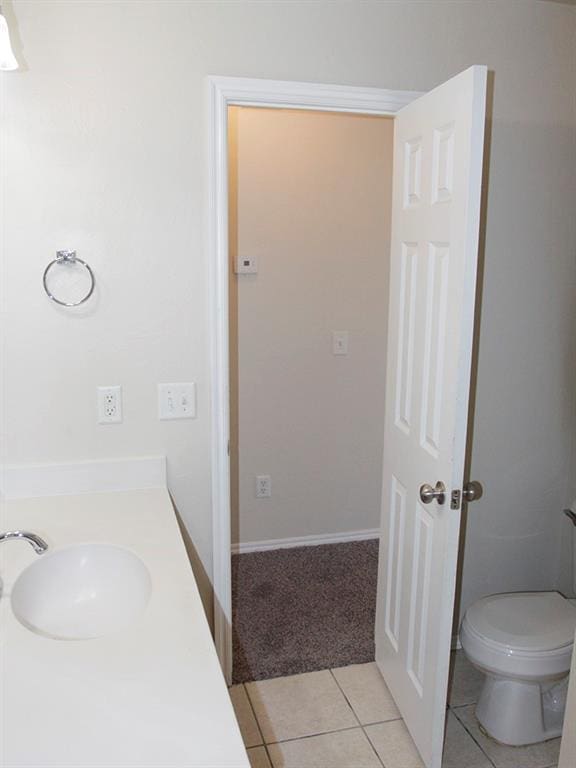 bathroom with toilet, a sink, and tile patterned floors