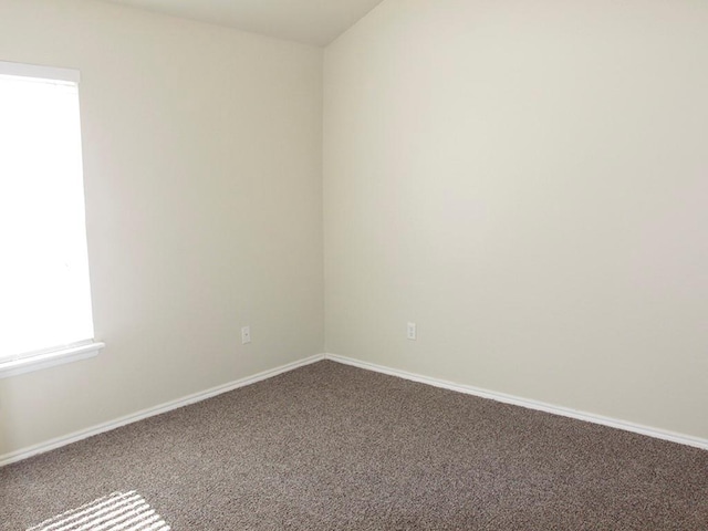 carpeted spare room featuring baseboards