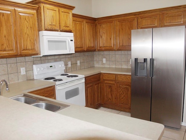 kitchen with white appliances, light tile patterned floors, brown cabinets, light countertops, and a sink