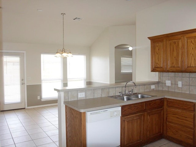 kitchen featuring white dishwasher, a peninsula, a sink, light countertops, and brown cabinetry