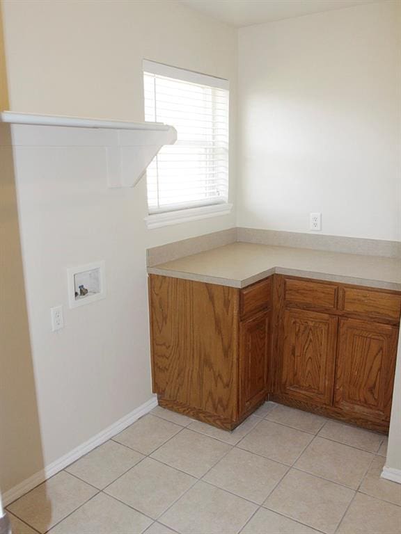 clothes washing area with laundry area, washer hookup, light tile patterned flooring, and baseboards