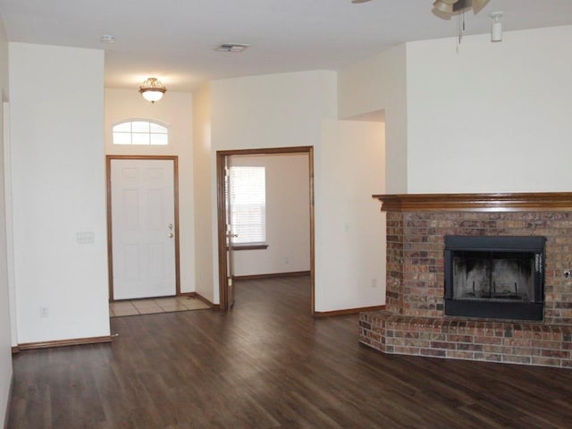 entrance foyer with baseboards, visible vents, dark wood finished floors, ceiling fan, and a brick fireplace