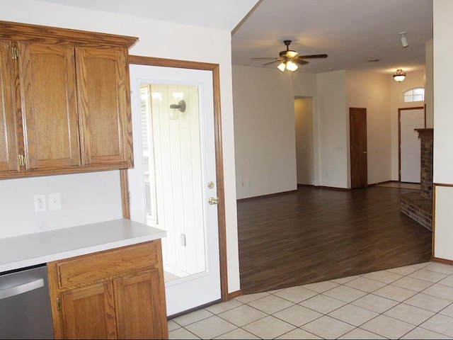 kitchen with brown cabinets, light tile patterned floors, light countertops, ceiling fan, and dishwasher