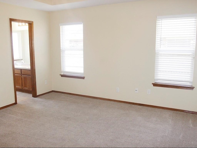 unfurnished room featuring baseboards and light colored carpet