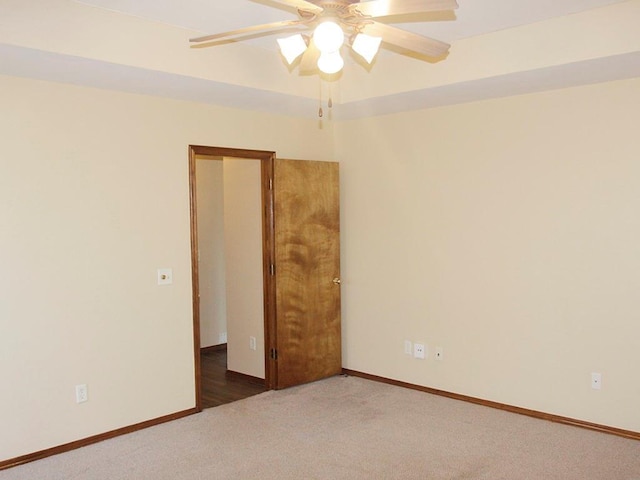 spare room featuring dark carpet, baseboards, and ceiling fan