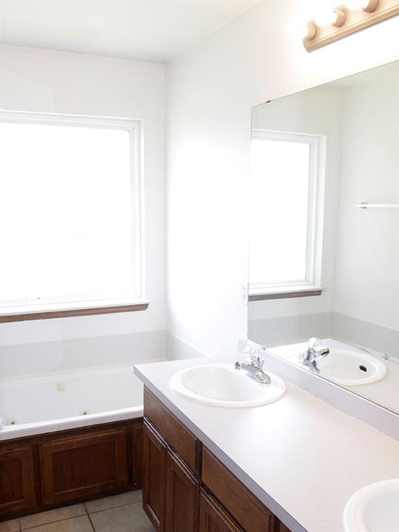 full bath featuring tile patterned flooring, double vanity, a sink, and a bath