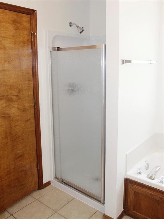 bathroom featuring tile patterned flooring, a bath, and a shower stall