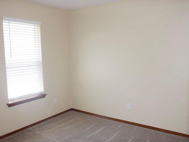 unfurnished room with carpet flooring and baseboards