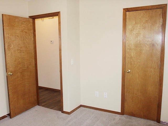 unfurnished bedroom featuring light carpet and baseboards