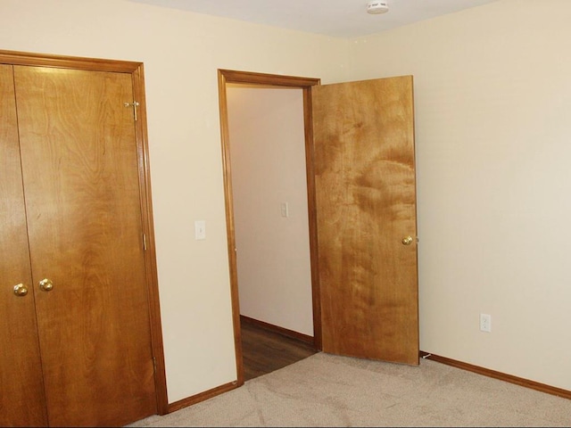 unfurnished bedroom with a closet, baseboards, and carpet flooring