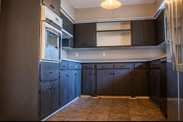 kitchen featuring dark tile patterned flooring, stainless steel refrigerator, oven, light countertops, and open shelves