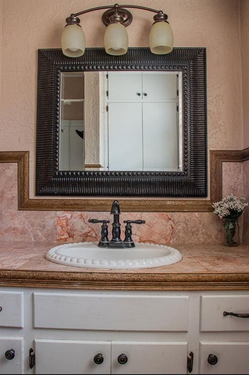 bathroom featuring a textured wall, tasteful backsplash, and vanity