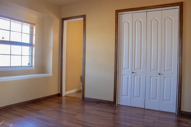 unfurnished bedroom with a closet, wood finished floors, and baseboards