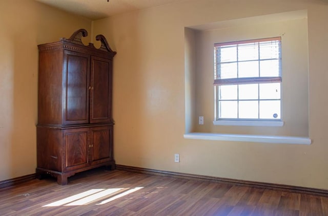 spare room featuring baseboards and wood finished floors