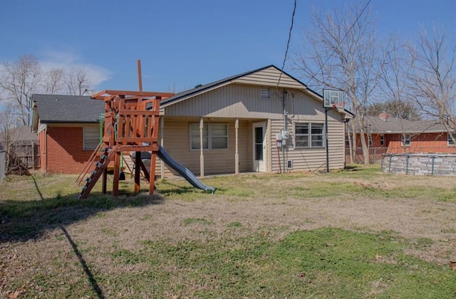 rear view of property with a playground, brick siding, a lawn, and fence