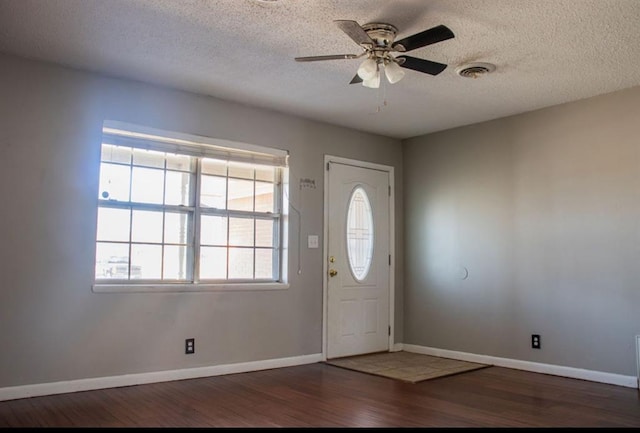 entryway with a textured ceiling, wood finished floors, visible vents, baseboards, and a ceiling fan