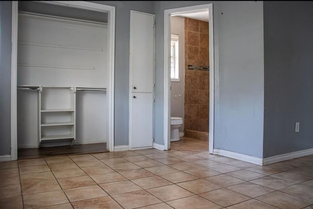 unfurnished bedroom featuring a closet, light tile patterned flooring, and baseboards