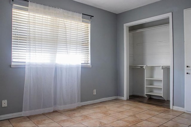 unfurnished bedroom featuring a closet, light tile patterned flooring, and baseboards