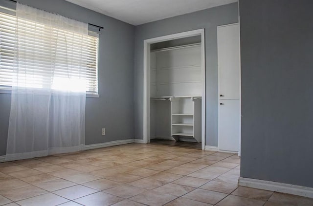 unfurnished bedroom featuring baseboards, a closet, and light tile patterned flooring