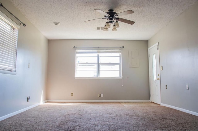 spare room with light carpet, ceiling fan, visible vents, and a textured ceiling