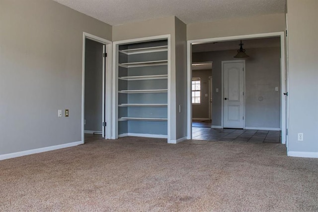 empty room featuring carpet flooring, a textured ceiling, and baseboards