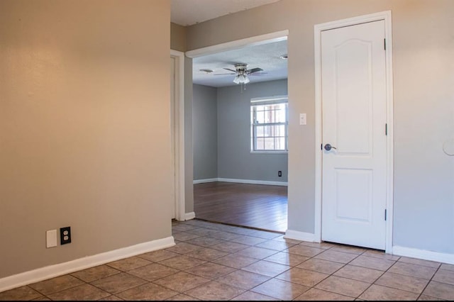 unfurnished room featuring light tile patterned flooring, a ceiling fan, and baseboards