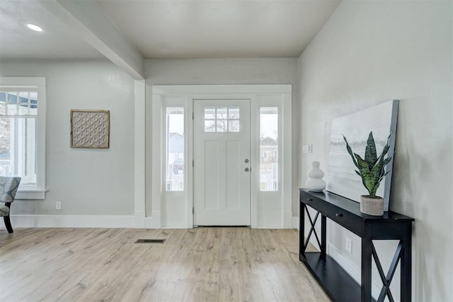 entryway with a wealth of natural light, visible vents, baseboards, and wood finished floors