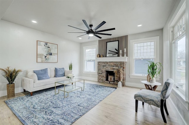 living area featuring recessed lighting, a stone fireplace, and wood finished floors