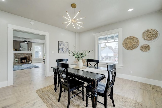 dining room with a chandelier, recessed lighting, a fireplace, baseboards, and light wood-style floors