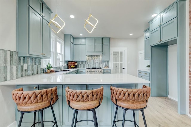 kitchen featuring a peninsula, tasteful backsplash, light countertops, and a sink