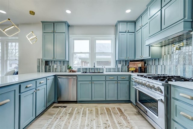 kitchen featuring custom range hood, appliances with stainless steel finishes, light countertops, and a sink