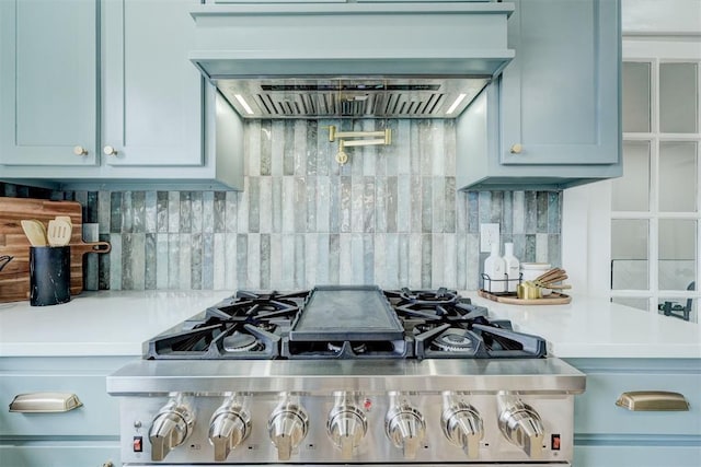 kitchen with stainless steel gas range, light countertops, premium range hood, and decorative backsplash