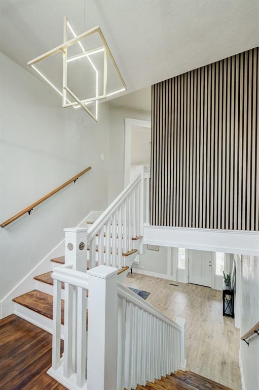 stairway featuring baseboards, a chandelier, and wood finished floors