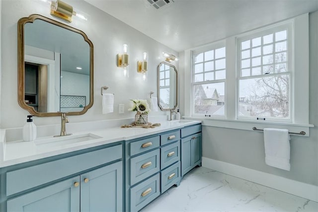 full bathroom featuring marble finish floor, a sink, baseboards, and double vanity