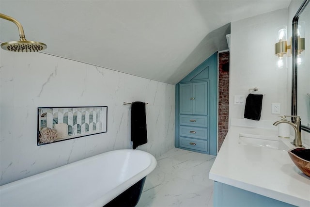 full bathroom with marble finish floor, double vanity, a sink, vaulted ceiling, and a freestanding tub