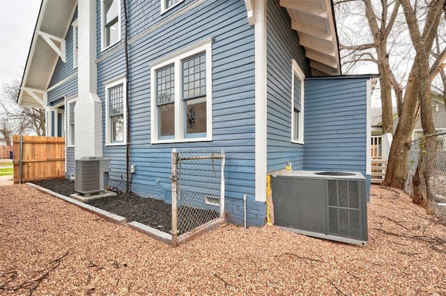 view of side of property featuring central AC and fence