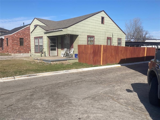 view of property exterior with a shingled roof and fence