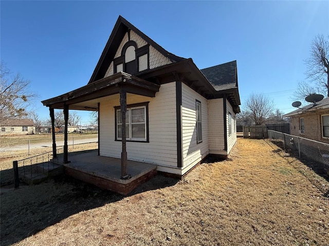 view of property exterior with a shingled roof and fence